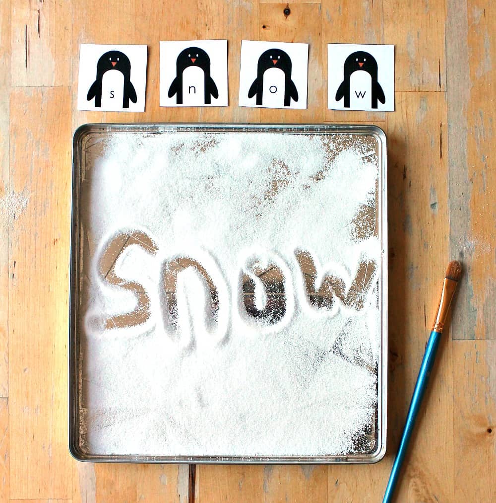 snow writing tray for literacy activity with a penguin theme